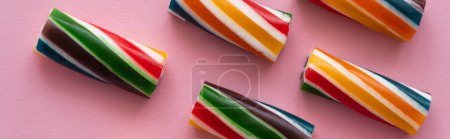 Foto de Vista superior de dulces caramelos rayados sobre fondo rosa, pancarta - Imagen libre de derechos