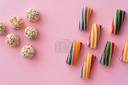 Płaskie leżaki z różnych kolorowych słodyczy na różowym tle 