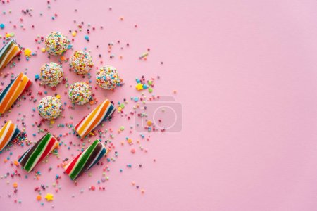 Vue du dessus de différents bonbons colorés et saupoudrer sur fond rose avec espace de copie 