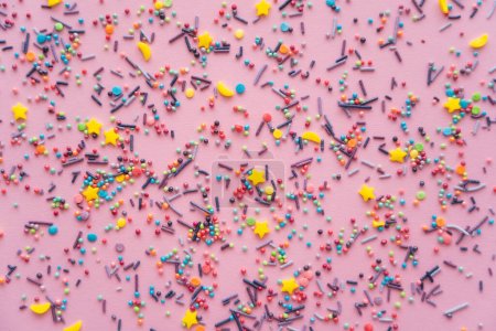 Top view of colorful sprinkles on pink background 