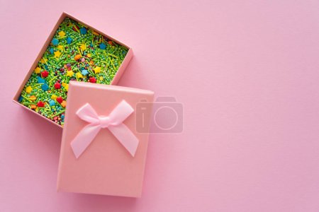 Téléchargez les photos : Vue du dessus des aspersions dans une boîte cadeau sur fond rose - en image libre de droit
