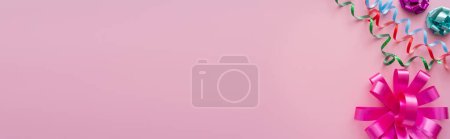 Photo for Top view of colorful serpentine and gift bows on pink background, banner - Royalty Free Image
