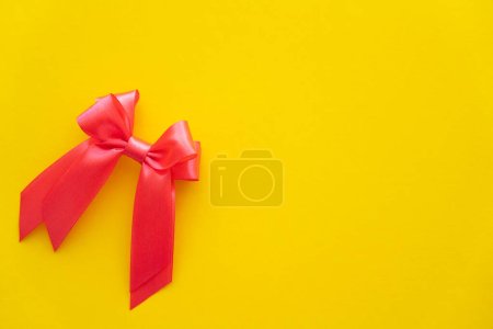 Top view of red bow with copy space on yellow background 