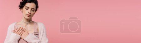 Téléchargez les photos : Jeune femme sensuelle avec les yeux fermés tenant la main sur la poitrine isolée sur rose, bannière - en image libre de droit
