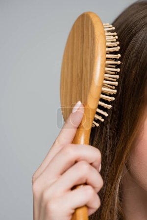 Photo for Close up view of cropped young woman brushing shiny and healthy hair isolated on grey - Royalty Free Image