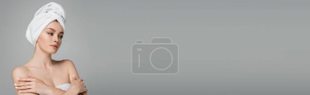 Téléchargez les photos : Jeune femme avec épaules nues et serviette sur la tête debout avec les bras croisés isolés sur gris, bannière - en image libre de droit