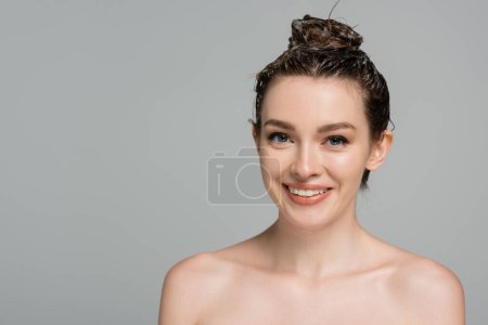 cheerful young woman with foam on head smiling isolated on grey 