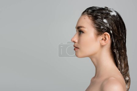 Foto de Vista lateral de mujer joven con el pelo espumoso y húmedo aislado en gris - Imagen libre de derechos