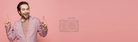Photo for Cheerful host of event pointing with fingers isolated on pink, banner - Royalty Free Image