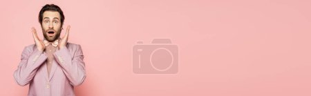 Photo for Shocked host of event in jacket and bow tie looking at camera isolated on pink, banner - Royalty Free Image