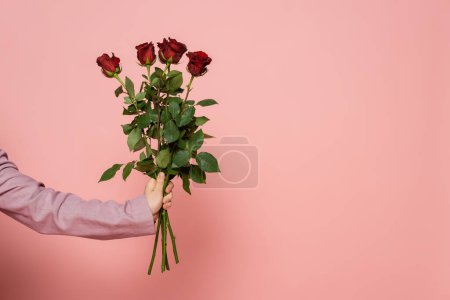 Widok na gospodarza imprezy w kurtce trzymając czerwone róże na różowym tle 
