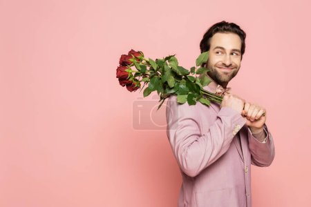 Cheerful host of event holding bouquet of flowers isolated on pink 