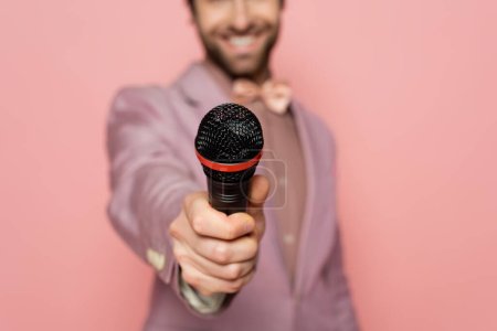 Photo for Cropped view of blurred host of event holding microphone isolated on pink - Royalty Free Image