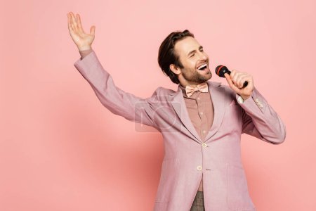 Photo for Brunette host of event singing at microphone on pink background - Royalty Free Image