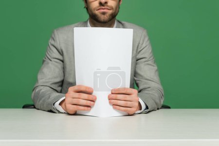 Photo for Cropped view of broadcaster in grey suit holding blank paper isolated on green - Royalty Free Image