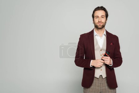 Photo for Young host of event in formal wear looking at camera while holding microphone isolated on grey - Royalty Free Image