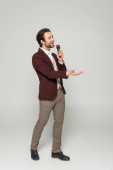 full length of bearded showman in formal wear singing in microphone on grey  mug #631513074