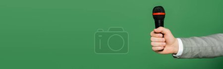 Photo for Cropped view of journalist holding microphone in hand isolated on green, banner - Royalty Free Image