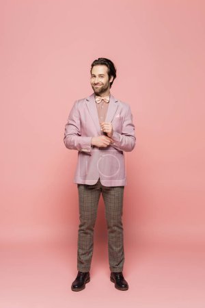 Foto de Longitud completa de showman alegre en traje con pajarita de pie en rosa - Imagen libre de derechos