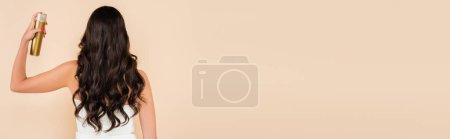 Photo for Back view of brunette woman using hairspray isolated on beige with copy space, banner - Royalty Free Image