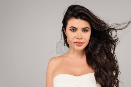 Photo for Portrait of pretty brunette woman in white top looking at camera isolated on grey - Royalty Free Image