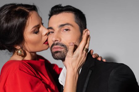 Foto de Elegant woman with makeup kissing boyfriend in formal wear on grey background - Imagen libre de derechos