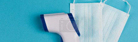 Top view pyrometer and protective masks on blue background, banner 