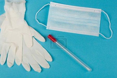 Top view of cotton swab near medical mask and latex gloves on blue background 