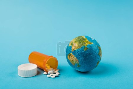 Foto de Globe and jar with pills from new omicron strain on blue background - Imagen libre de derechos