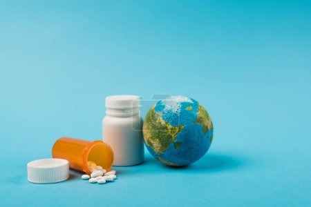 Téléchargez les photos : Globe and jars with pills from new omicron strain on blue background - en image libre de droit