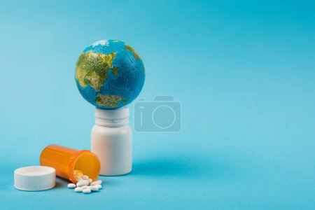 Small globe on globe with pills from new omicron strain on blue background 