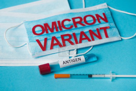Photo for Test tube with antigen lettering near medical masks and syringe on blue background - Royalty Free Image