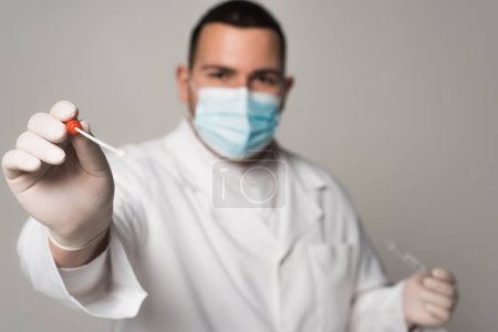 Blurred scientist in latex gloves holding throat swab isolated on grey 