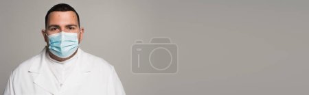 Photo for Scientist in medical mask looking at camera isolated on grey with copy space, banner - Royalty Free Image