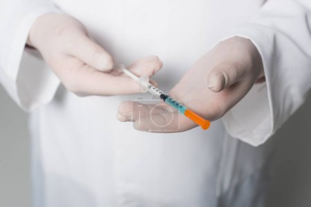 Foto de Cropped view of doctor in latex gloves holding syringe with vaccine on grey background - Imagen libre de derechos