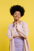pleased african american woman with curly hair looking at camera isolated on yellow puzzle #635603780
