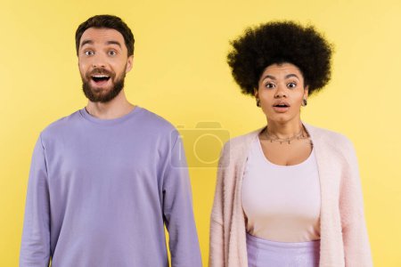 Téléchargez les photos : Surprised bearded man and curly african american woman standing with open mouth isolated on yellow - en image libre de droit