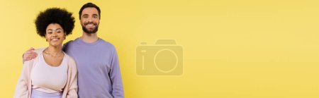 Photo for Joyful bearded man embracing shoulders of african american woman isolated on yellow, banner - Royalty Free Image