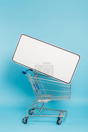 Téléchargez les photos : Shopping cart with huge template of mobile phone on blue background - en image libre de droit