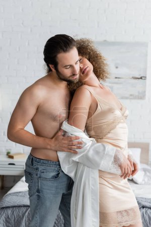 Photo for Shirtless man in jeans standing with seductive woman in night dress and silk robe - Royalty Free Image
