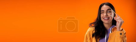 Photo for Young woman holding bamboo chopsticks and winking isolated on orange, banner - Royalty Free Image