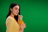 brunette woman with closed eyes enjoying fresh lemonade isolated on green puzzle #635936690