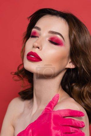 Téléchargez les photos : Portrait of young woman with magenta color eye shadow and closed eyes isolated on pink - en image libre de droit