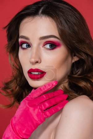 portrait of pretty woman with magenta color eye shadow looking away isolated on pink 