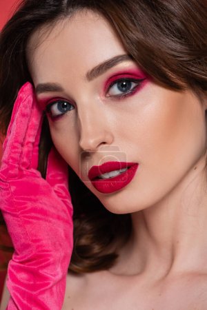 close up of young woman with magenta color eye shadow isolated on pink 
