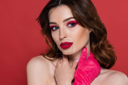 portrait of young woman with magenta color eye shadow and bright glove posing isolated on pink 
