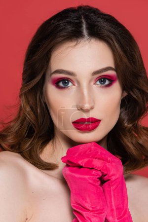 Téléchargez les photos : Portrait of young woman with magenta color gloves standing with clenched hands isolated on pink - en image libre de droit