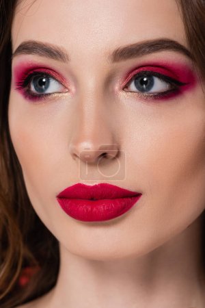 close up of young woman with magenta color makeup looking away 