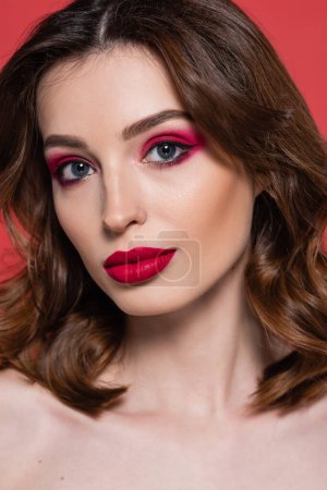 portrait of young woman with magenta color makeup and bright lipstick looking at camera isolated on pink 