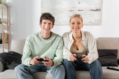 Foto de KYIV, UKRAINE - OCTOBER 24, 2022: happy young couple playing video game at home - Imagen libre de derechos